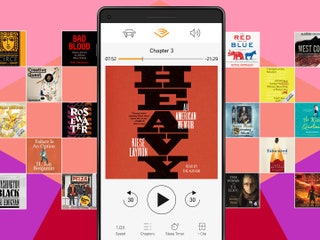 Audible app on smartphone surrounded by books